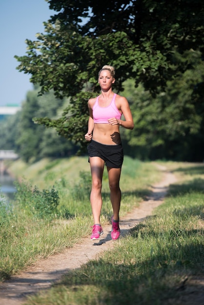 Jonge vrouw loopt in bebost bosgebied - opleiding en oefenen voor Trail Run Marathon uithoudingsvermogen - Fitness gezonde levensstijl Concept