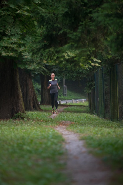 Jonge vrouw loopt in bebost bosgebied - opleiding en oefenen voor Trail Run Marathon uithoudingsvermogen - Fitness gezonde levensstijl Concept