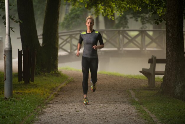 Jonge vrouw loopt in bebost bosgebied - opleiding en oefenen voor Trail Run Marathon uithoudingsvermogen - Fitness gezonde levensstijl Concept