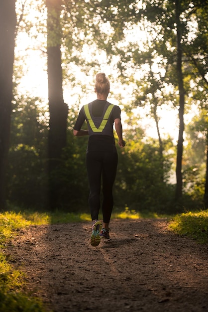 Jonge vrouw loopt in bebost bosgebied - opleiding en oefenen voor Trail Run Marathon uithoudingsvermogen - Fitness gezonde levensstijl Concept