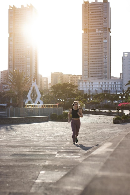 Jonge vrouw loopt in de stad bij zonsondergang