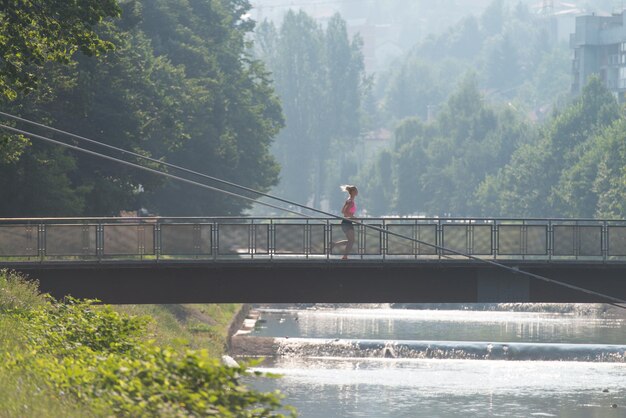 Jonge vrouw loopt op brug In bebost bosgebied - opleiding en oefenen voor Trail Run Marathon uithoudingsvermogen - Fitness gezonde levensstijl Concept