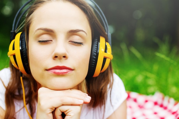 Jonge vrouw luisteren naar muziek in moderne koptelefoon op weide