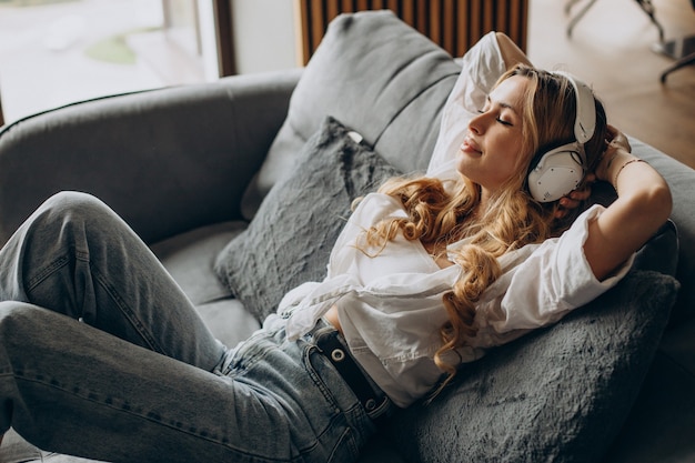 Jonge vrouw luistert naar muziek in oortelefoons in haar appartement