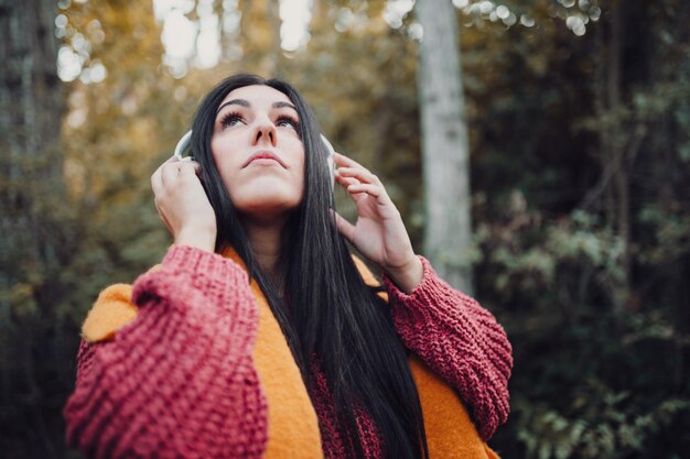 Foto jonge vrouw luistert naar muziek met haar koptelefoon in het bos