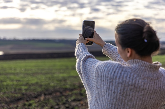 Jonge vrouw maakt een foto van het veld met smartphone