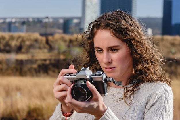 Jonge vrouw maakt foto's op haar vakanties, met retro fotocamera in het veld.