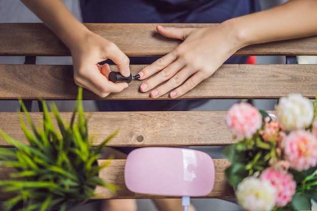 Jonge vrouw maakt manicure met gellak en UV-lamp in roze tinten