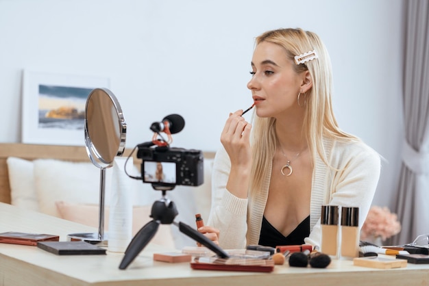 Jonge vrouw maakt schoonheid en cosmetische tutorial video-inhoud voor sociale media Schoonheid blogger met behulp van camera en licht ring terwijl het laten zien hoe vloeibare lippenstift aan te brengen aan publiek of volger Blithe