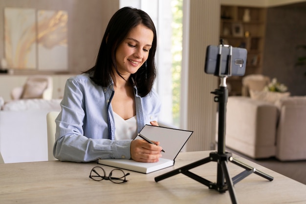 Foto jonge vrouw maakt thuis een vlog met haar telefoon