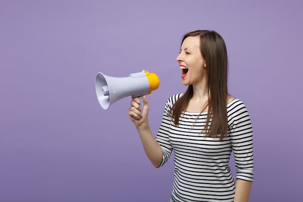 Jonge vrouw meisje in casual gestreepte kleding poseren geïsoleerd op violette achtergrond studio portret. Mensen levensstijl concept. Bespotten kopie ruimte. Schreeuw in megafoon, kondigt kortingen aan, schiet op.