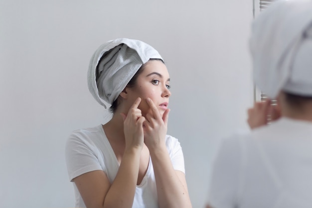 Jonge vrouw met acne in badkamer