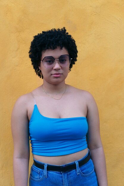 Jonge vrouw met afro kapsel en zonnebril serieus kijken naar de camera.