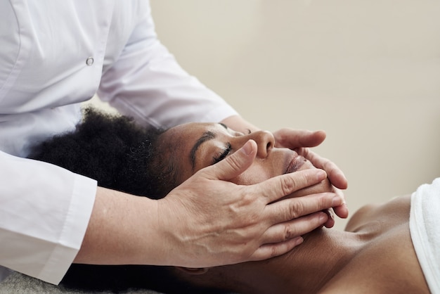 Jonge vrouw met antistress gezichtsmassage in salon in kuuroord. Gezichtsmassage.