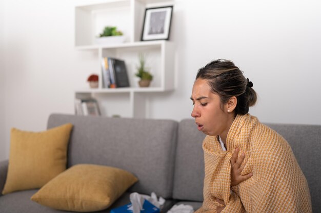 Jonge vrouw met astma luid hoestend bedekt met een deken