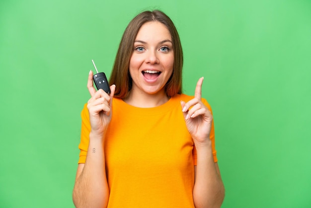 Jonge vrouw met autosleutels over geïsoleerde chroma key achtergrond die een geweldig idee benadrukt