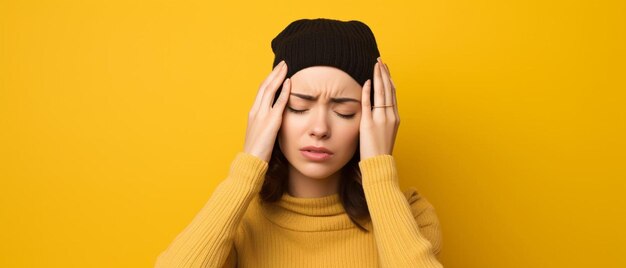 Foto jonge vrouw met baret met hoofdpijn op gele achtergrond