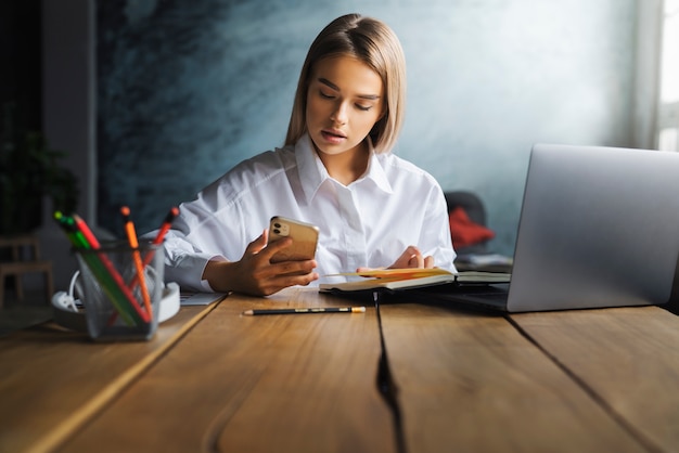 Jonge vrouw met behulp van aangesloten digitale apparaten voor werk en communicatie