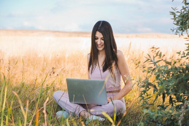 Jonge vrouw met behulp van de laptop in het veld