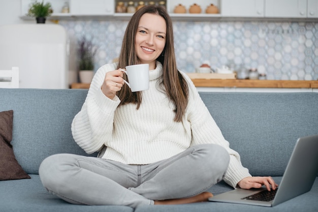 Jonge vrouw met behulp van een laptop in een gezellig appartement