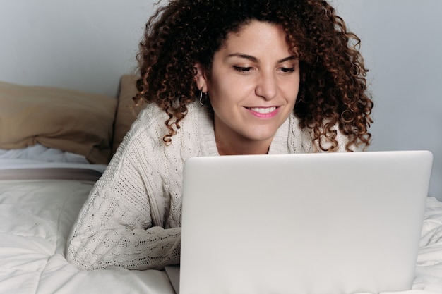 Jonge vrouw met behulp van haar laptop op bed