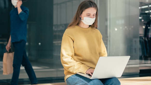 Jonge vrouw met behulp van haar laptop op straat tijdens quarantaine