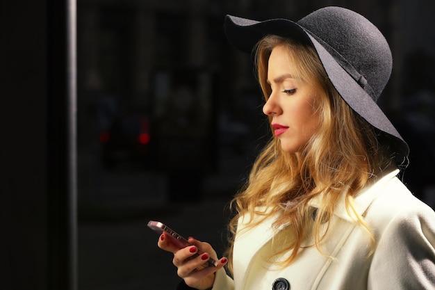 Jonge vrouw met behulp van mobiele telefoon in de straat 's avonds tijd