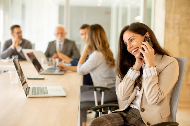 Jonge vrouw met behulp van mobiele telefoon op kantoor