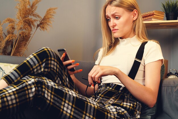 Jonge vrouw met behulp van mobiele telefoon. Zittend op de bank.