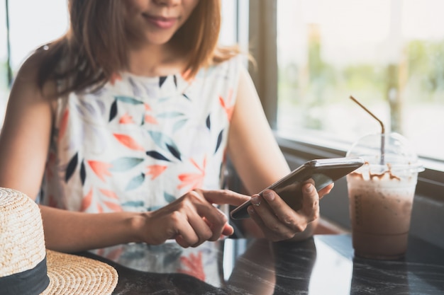 Jonge vrouw met behulp van slimme telefoon met drankjes in café