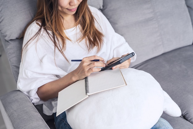 Jonge vrouw met behulp van smartphone aan gezellige huis op sofa in de woonkamer