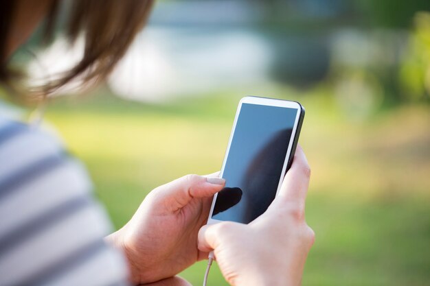 Jonge vrouw met behulp van smartphone in park in zonsondergang