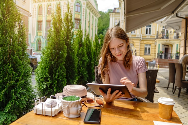 Jonge vrouw met behulp van tablet-pc in een café op een zomerterras