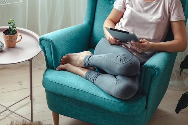 Jonge vrouw met behulp van tablet zittend in een comfortabele stoel