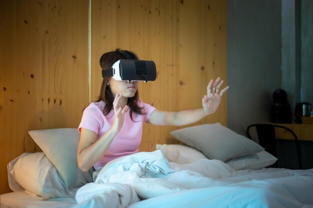 Foto jonge vrouw met behulp van virtual reality-headset in bed vr toekomstige digitale technologie game films entertainment metaverse nft en 3d cyberspace concept