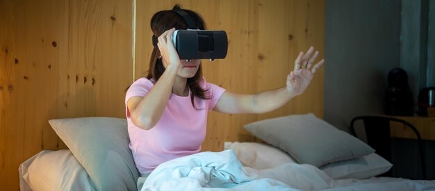 Jonge vrouw met behulp van virtual reality-headset in bed VR Toekomstige digitale technologie game films entertainment metaverse NFT en 3D cyberspace concept