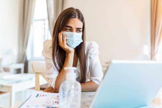 Jonge vrouw met beschermend masker vanuit huis werken