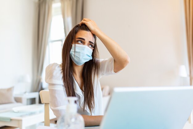 Jonge vrouw met beschermend masker vanuit huis werken