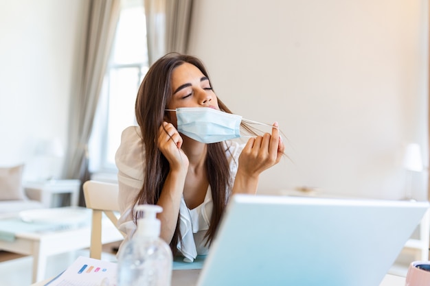 Jonge vrouw met beschermend masker vanuit huis werken