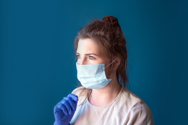 Jonge vrouw met beschermende handschoenen en gezichtsmasker in een huis in quarantaine op zoek verveeld en verdrietig, voor Covid-19 Coronavirus