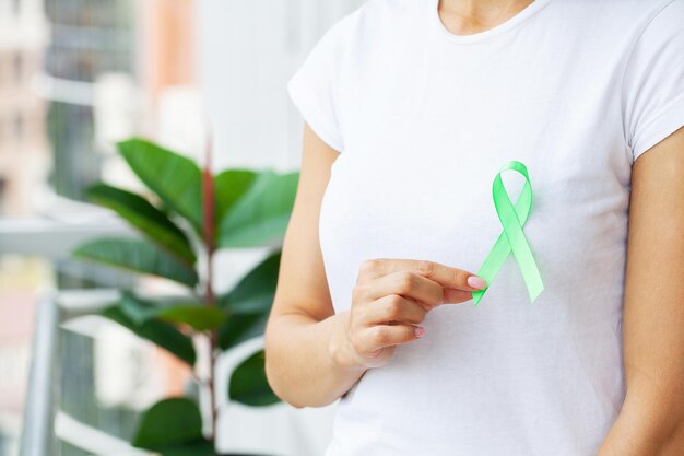 Jonge vrouw met bewustzijnsgroen lint als symbool voor bewustzijnslymfoomkanker