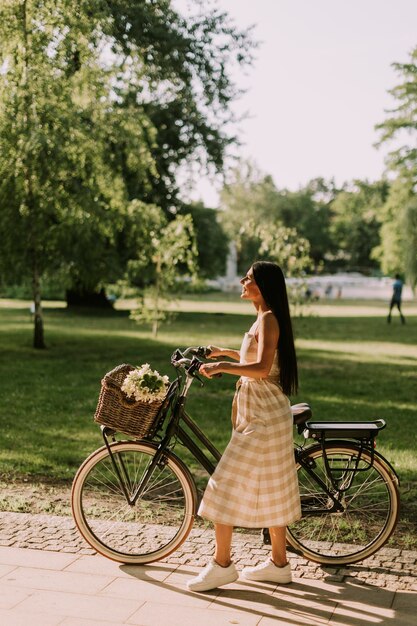 Jonge vrouw met bloemen in de mand van elektrische fiets