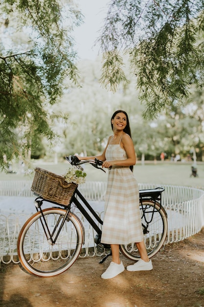 Jonge vrouw met bloemen in de mand van elektrische fiets