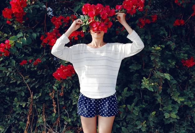 Foto jonge vrouw met bloemen terwijl ze bij planten in het park staat