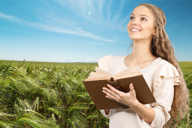 Jonge vrouw met boek in veld op zomerdag