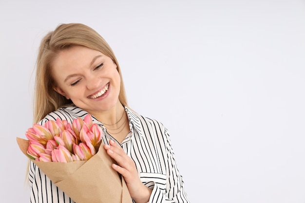 Jonge vrouw met boeket bloemen op witte achtergrond