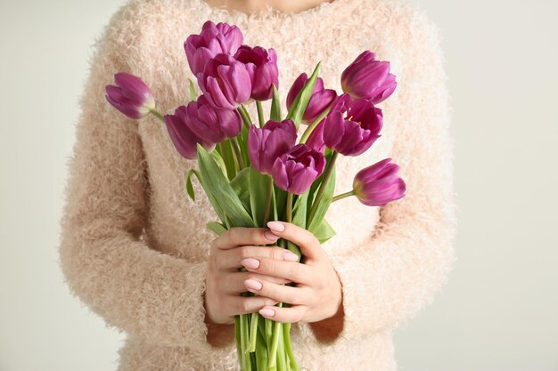 Jonge vrouw met boeket van mooie lila tulpen op witte achtergrond closeup