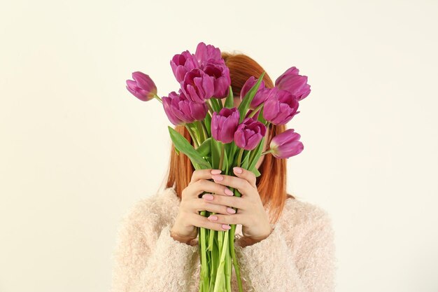 Jonge vrouw met boeket van mooie lila tulpen op witte achtergrond