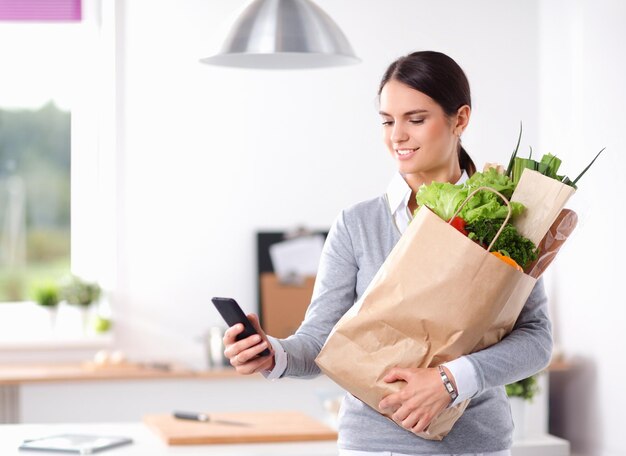 Jonge vrouw met boodschappentas met groenten die in de keuken staan