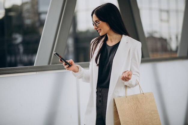 Jonge vrouw met boodschappentassen praten aan de telefoon